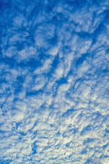 Beautiful waves of clouds against bright blue sky.