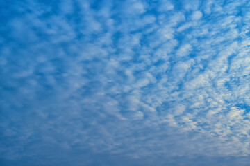 Beautiful waves of clouds against bright blue sky.