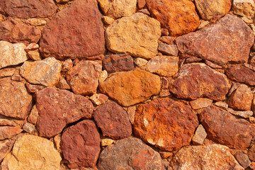 Fondo de rocas rojizas. Pared de mampostería moderna en un parque público, Las Negras, España.