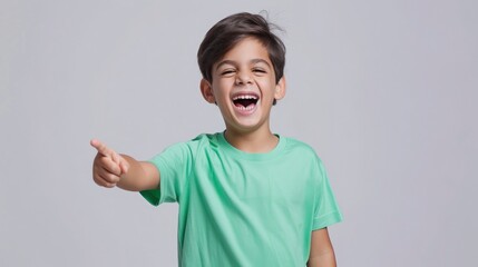 A boy in a plain green t-shirt, laughing and pointing towards. mockup concept