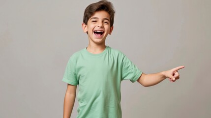 A boy in a plain green t-shirt, laughing and pointing towards. mockup concept