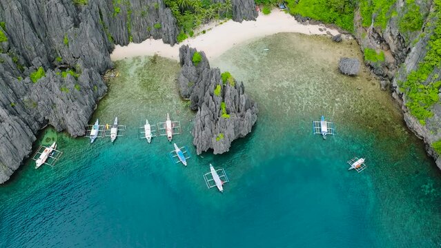 Beautiful rock formations in Secret Lagoon. Jiji's Beach with white sand and boats. El Nido, Palawan. Philippines.