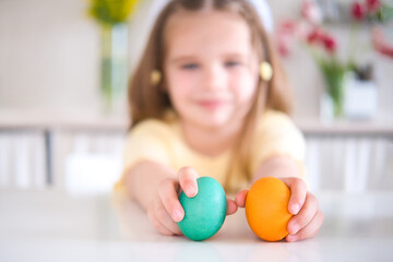 Fototapeta na wymiar happy little girl playing with easter eggs at kitchen. celebrate Easter at home. selective focus