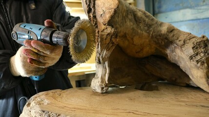 processing wood with a sander with a metal round bristle disk in a carpenter's workshop, sanding a piece of solid wood in the process of producing wooden carpentry