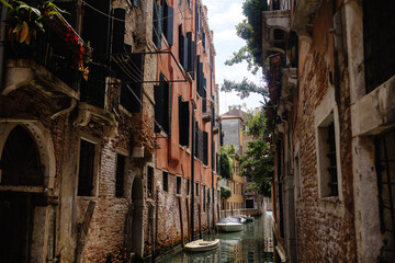 Fototapeta na wymiar A narrow canal in Venice, Italy, with buildings on both sides and a boat floating in the water.
