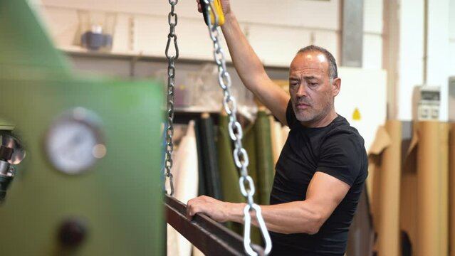 caucasian labor controlling a mechanical Overhead crane for moving heavy stuff inside a factory working class concept