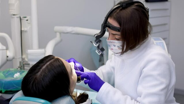 A young woman is undergoing treatment in a modern dental clinic. The concept of dental treatment, whitening, installation of veneers and braces, cleaning the oral cavity.