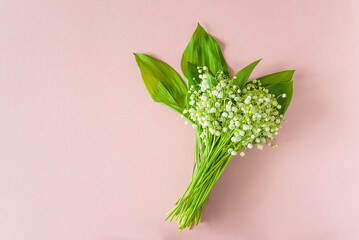 May Day symbol: bouquet of lilies-of-the-valley on a pink background; flat lay, copy space