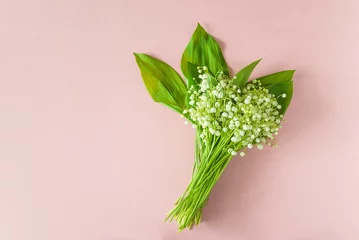 May Day symbol: bouquet of lilies-of-the-valley on a pink background  flat lay, copy space © stsvirkun