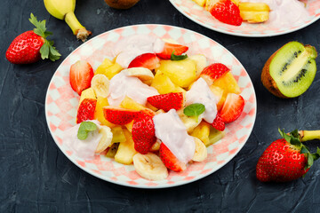 Fruit juicy salad with yogurt on a plate.