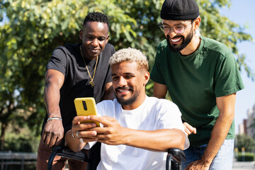 Man on wheelchair together with friends using mobile phone to share content on social media