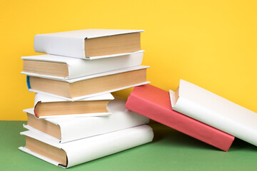 Books stacking. Open hardback books on wooden table and green background. Back to school. Copy space for ad text.