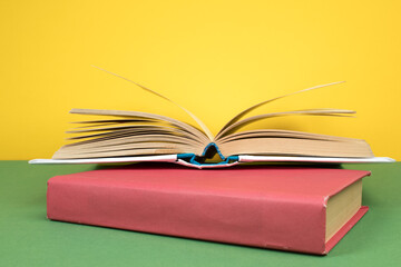 Books stacking. Open hardback books on wooden table and green background. Back to school. Copy space for ad text.