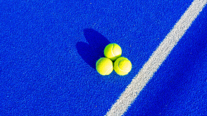 Detail of a new synthetic padel court. White lines on a blue artificial grass tennis court. Yellow balls. Racket sports concept