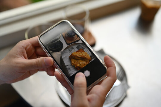 Close-up of the male's hands photographing breakfast in a cafe with a smartphone