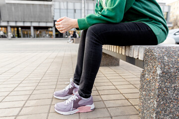 woman in sportswear and sneakers sits on bench