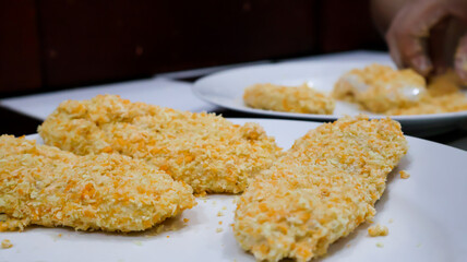 Close-up of a woman making fried banana by coating the banana in golden bread crumb to then be fried. Ideal for food blogs, cooking concepts, food enthusiasts, and cooking-themed designs. 