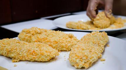 Close-up of a woman making fried banana by coating the banana in golden bread crumb to then be fried. Ideal for food blogs, cooking concepts, food enthusiasts, and cooking-themed designs. 