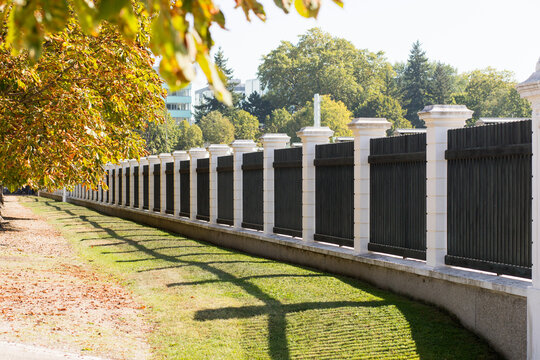 A long bridge stretching into the distance, sunny autumn weather. High parkan. Beautiful fence with concrete pillars. Fencing of the park area. Walk in nature.