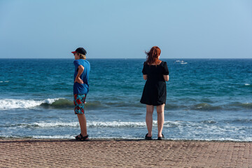 Two teenagers on a promenade by the sea in summer
