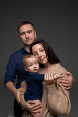 close-up portrait of happy parents hugging their little son and holding them in their arms. minimalistic photography on a dark background. father and mother with little son