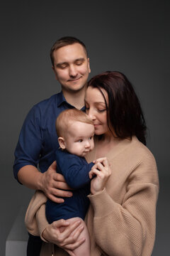 close-up portrait of happy parents hugging their little son and holding them in their arms. minimalistic photography on a dark background. father and mother with little son