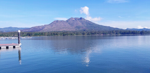 Panoramic view of a lake surrounded by mountain, tropical landscape with colorful clouds in the sky. Gunung Batur, Kintamani, Bali