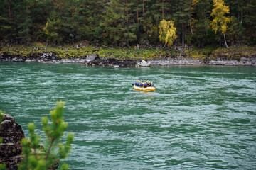 A yellow inflatable rubber boat with rafters in blue life jackets and yellow helmets are rafting on...