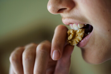 Crop anonymous girl eating fresh healthy walnut at home