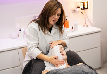 Obraz na płótnie Canvas Woman beautician treating client in beauty salon