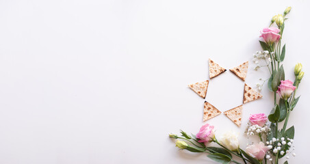 Passover. banner of Traditional Matzo shape of star Magen David  decorate by pink flowers on white background. top view. Holiday of Jewish people, Spring Holiday. Fasting time