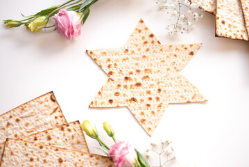 Passover. Traditional Matzo shape of star Magen David  decorate by pink flower on white background. top view. Holiday of Jewish people, Spring Holiday. Fasting time