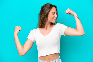 Young caucasian woman isolated on blue background doing strong gesture