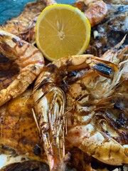 king prawns cooked in soy sauce are served on a large plate with lemon