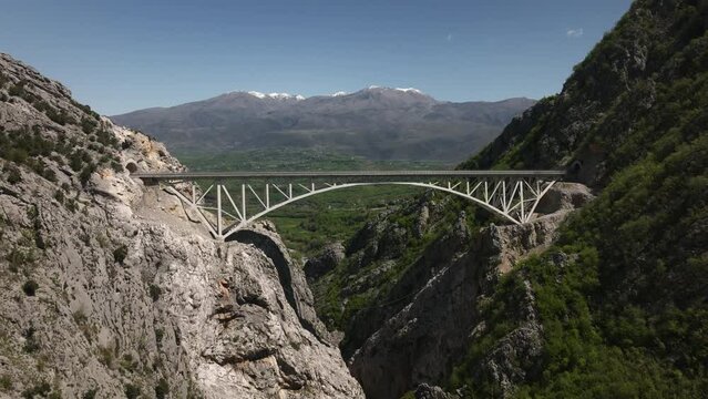 Aerial view of Ura e Lezedr&euml;s, Klos - Arbri Road bridge in Albanian mountains, blue sky and snowy summit in the background