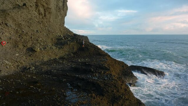 Aerial: Rocky coastline of the waitakere ranges at sunset, Whites beach, Auckland, New Zealand.