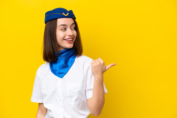 Airplane stewardess Ukrainian woman isolated on yellow background pointing to the side to present a product