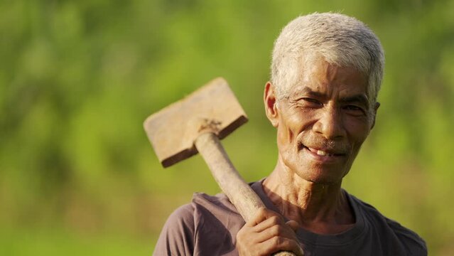 portrait of senior asian farmer in rural asia with traditional tool, subsistence farming