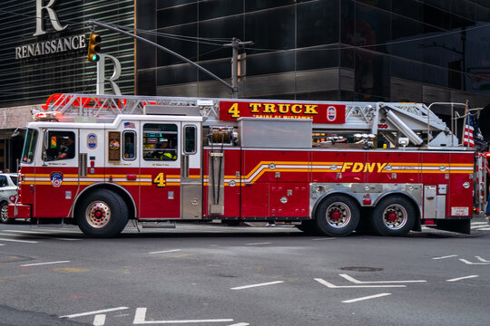 Manhattan, New York - June 23 2023 : Big Red Firetruck number 4 drives through the busy Manhattan streets at a crosswalk close to Times Square. Bright and colourful vehicle moving through urban city