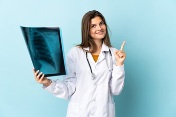 Young doctor woman holding radiography over isolated background showing and lifting a finger in...