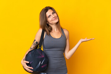 Slovak sport woman with sport bag isolated on yellow background extending hands to the side for...