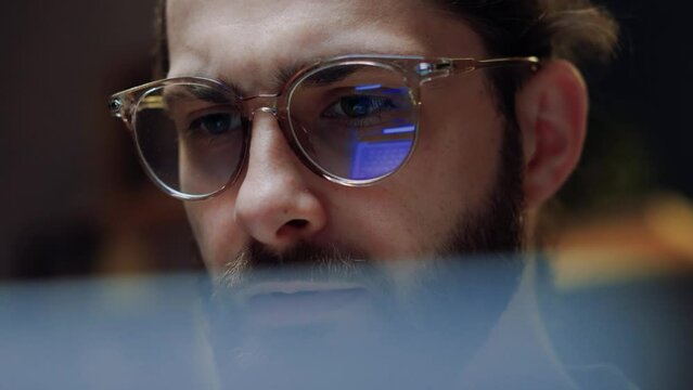 Close up eye reflection. Focused crypto trader analyst wearing eyeglasses working looking at computer screen reflecting in glasses analyzing online trading stock exchange market data charts.