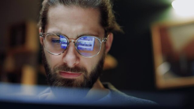 Close up portrait of handsome young man in glasses working on modern digital gadget at home at night time. Strategy, laptop and man doing remote work for planning, freelancing or typing.