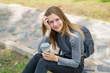 Young blonde woman at outdoors holding a take away coffee