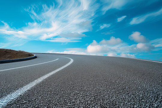 A road is curving down on a blue sky.
