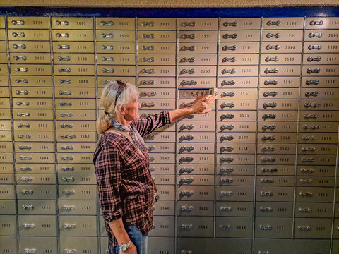 A older woman opens her secret box with deposits in a bank vault. Pensioner.