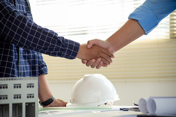 Fototapeta premium Architect and engineer construction workers shaking hands after successful collaboration.