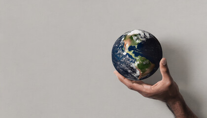 Top view of a human hand holding planet earth on a wall background
