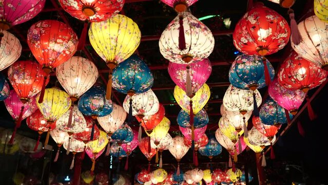 Multiple hanging colorful lantern as decoration for Chinese New Year celebration, swaying in wind. Night view.