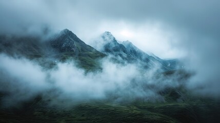Majestic mountains wear a crown of clouds, their peaks peeking through the mist.